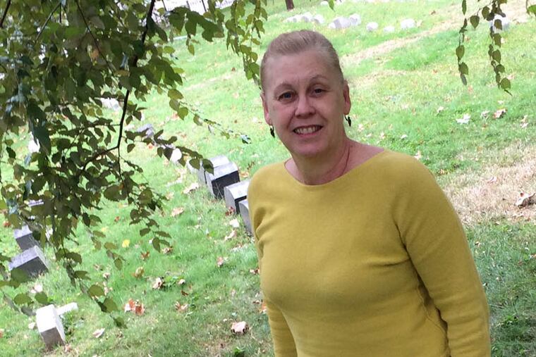 Brandi Levine, executive director of Fair Hill Burial Ground, will guide Saturday's 'Waking the Dead Tour' of four historical burial grounds on Germantown Avenue. She is standing by abolitionist Lucretia Mott's grave. DAN GERINGER / Daily News Staff