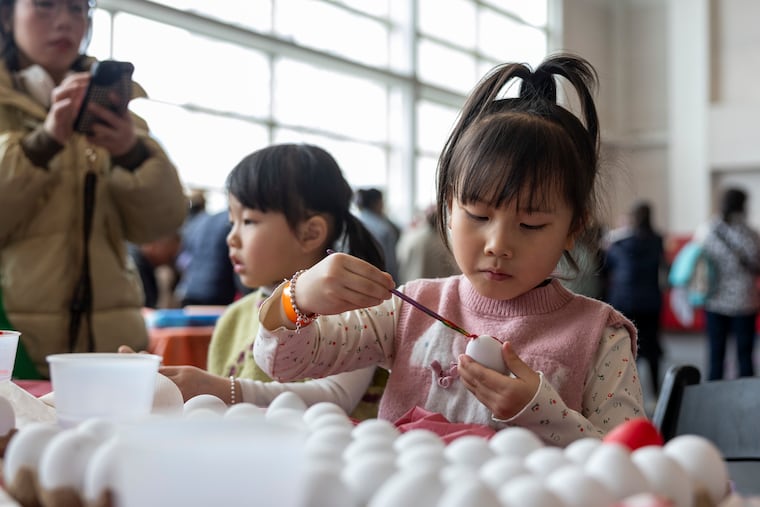 Connie Ni (right), and her sister, Bella, decorate their eggs during the Philadelphia Chinatown Development Corp.'s Easter egg hunt at the Crane Community Center in Chinatown.