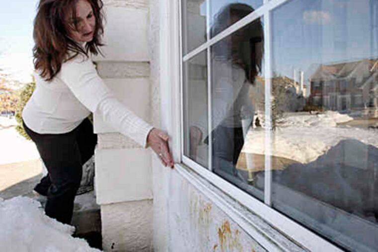 Lisa Ruffner of Voorhees points to windows that she said leaked and allowed mold to form in the moist stucco of the wall. (Elizabeth Robertson / Staff)