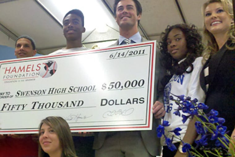 Phillies pitcher Cole Hamels and wife Heidi present a check for $50,000 at Swenson High School on Tuesday. (Drew Singer / Staff Photo)