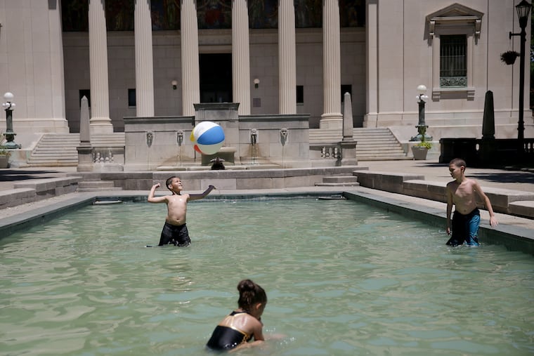 Willfredo Sosa, 10, left, hits a beach ball as he plays with his brother, Eliud Sosa, 11, right, and Melinda Rivera, 3, center, in the reflecting pool in front of Cooper Library in Johnson Park in Camden on Thursday when the high temperature for the day was 92.