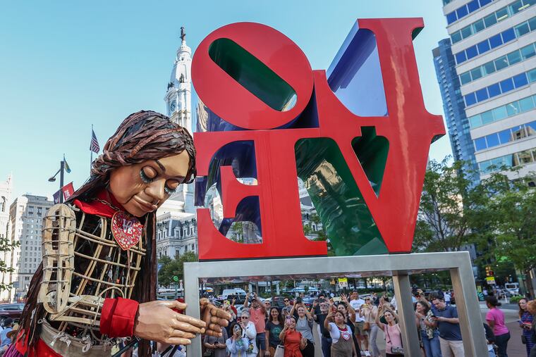 Little Amal rests her head on the LOVE sign at LOVE Park on Sept. 14, 2023. Little Amal, a 12-foot puppet of a 10-year-old Syrian refugee girl, has become a global symbol of the plight of refugees and their human rights since she was first created two years ago.