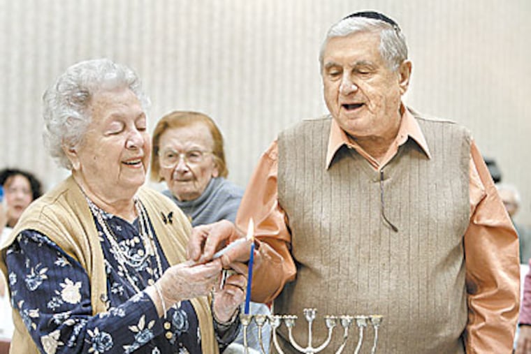 Lili and Emil Paul from Marlton, NJ light a hanukkah candle. Both are Holocaust survivors. (Akira Suwa / StaffPhotographer )