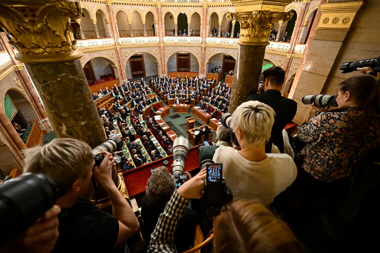 Photographers take pictures as Hungarian Prime Minister Viktor Orban, center right, stands after addressing a parliament session, on the day lawmakers are expected to approve Sweden's accession into NATO, in Budapest, Hungary.