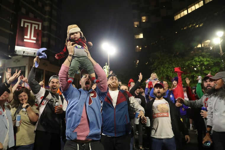 Ben Siegel-Wallace held up his 9-month old, Elliyas, as fans celebrated at Broad and Locust Streets in Philadelphia after the Phillies defeated the Padres on Sunday to move on to the World Series.