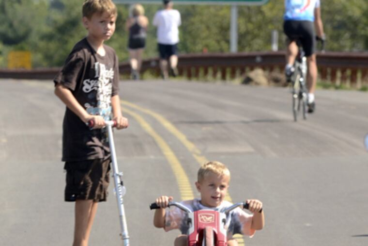 Zachary Schultz, 4, and his brother Nicholas, 10, explore the Route 22 Parkway at the exit for Route 611 near the trailhead parking area at New Britain Road in Doylestown. (Tom Gralish / Staff Photographer)