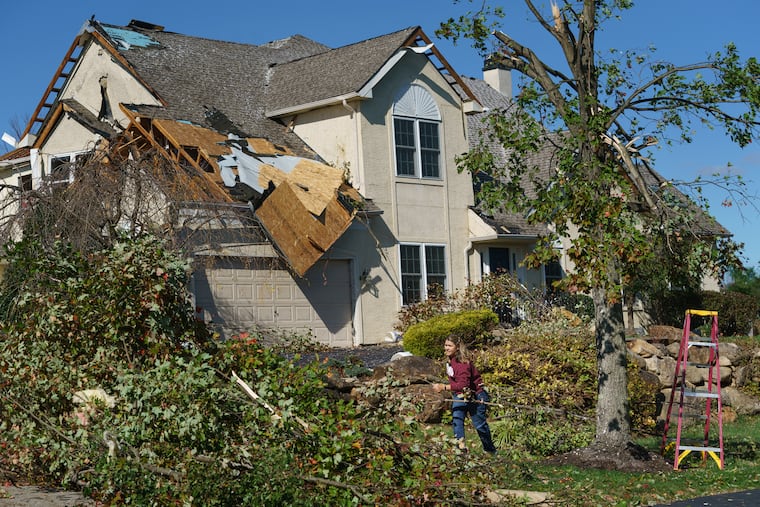Cindy Bevilacqua moves branches in her daughter's yard, after an EF-2 tornado ripped through Chelsea Court in Thornbury Township.