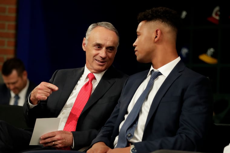 In this June 3, 2019, file photo, Major League Baseball Commissioner Rob Manfred, left, talks to Brennan Malone, a right-handed pitcher from IMG Academy in Bradenton, Fla., during the first round of last year's amateur draft in Secaucus, N.J. MLB will be cutting this year's draft from 40 rounds down to five.