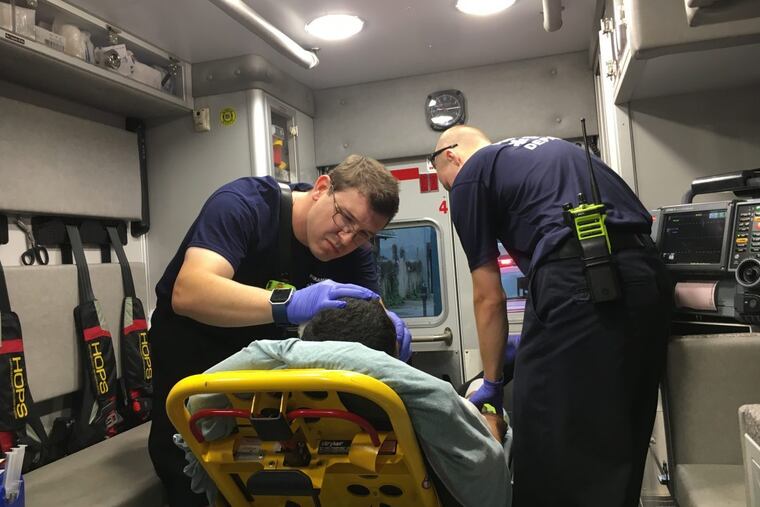 David Sullivan, left, a paramedic, and Brent Helvig, an EMT, treat a man suspected of overdosing on heroin in Philadelphia in June.