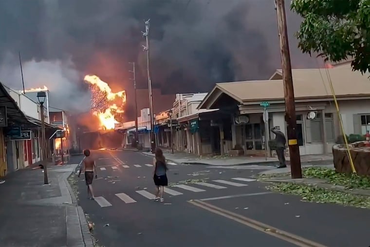People watch as smoke and flames fill the air from raging wildfires on Front Street in downtown Lahaina, Maui. Maui officials say wildfire in the historic town has burned parts of one of the most popular tourist areas in Hawaii. County of Maui spokesperson Mahina Martin said in a phone interview early Wednesday says fire was widespread in Lahaina, including Front Street, an area of the town popular with tourists.
