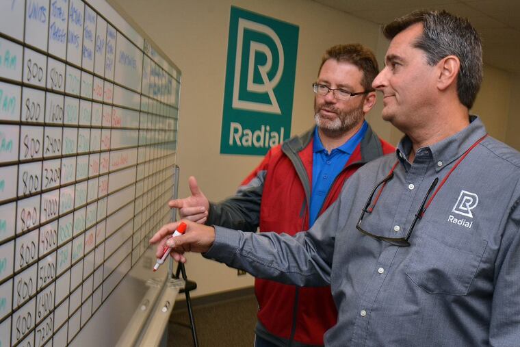 Radial HR manager Patrick Koreck (left) and director of fulfillment operations Alex Economos go over a daily productivity board at their new fulfillment center (warehouse) in Burlington City.