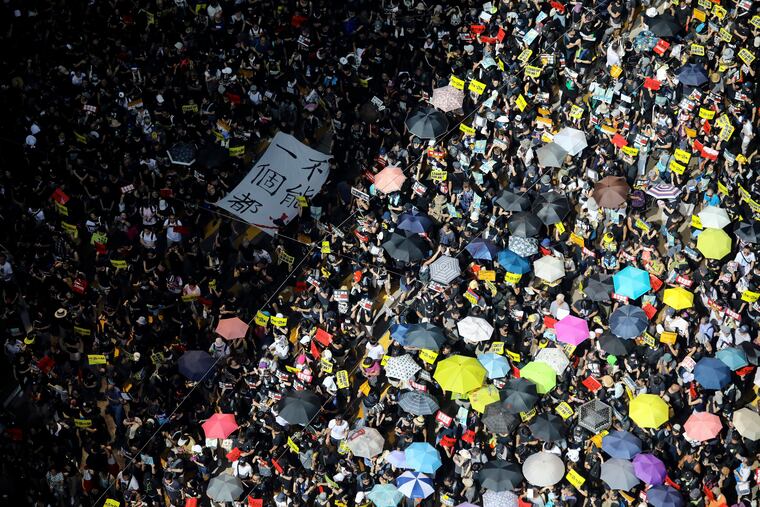 Protesters march with a banner which reads "Not one less" in Hong Kong on Monday, July 1, 2019. The embattled leader of Hong Kong pledged Monday to be more responsive to public sentiment, as police faced off with protesters on the 22nd anniversary of the former British colony's return to China. (Karma Lo/HK01 via AP)