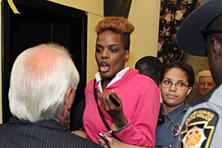 Colwyn Borough police put Kimberly Brown in handcuffs as she has words with Mayor Daniel Rutland (back to camera) during a raucous Borough Council meeting Thursday night. Brown was escorted out of the meeting for allegedly being disruptive; it was unclear whether she was charged. MICHAEL BRYANT / Staff Photographer