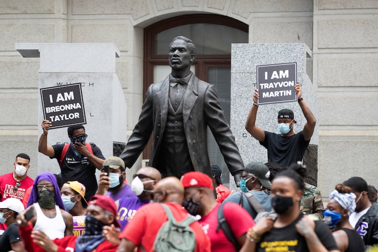 Signs are held on each side of A Quest for Parity: The Octavius V. Catto Memorial during the The Divine 9 United for Equality & Justice rally held by black fraternities on June 6, 2020 in a demonstration against police brutality and racial injustice after the death of George Floyd.