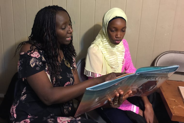 Aminata Sy reads to Dieynaba, an eighth grader from Senegal.