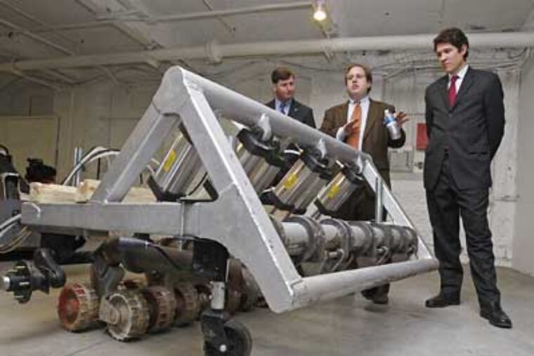 U.S. Rep. Patrick J. Murphy (left) listens to Joshua Koplin (center) and Samuel Reeves, of Humanistic Robotics, Inc., explain how their robotic minesweeper works.