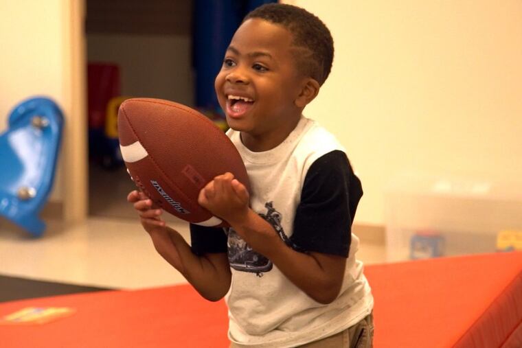 Zion Harvey catches a football during physical therapy at CHOP.