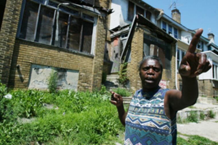 Pat Bryant, block captain for the 5600 block of Beaumont Street in Southwest Philadelphia, says she has futiley sought city rehab funding for the houses behind her. She points to a house across the street that is being privately developed.