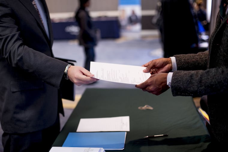 A job seeker hands a resumé to a recruiter at a career fair in Dearborn, Mich., in 2017. Now more people are using AI tools to apply for jobs, and employers are using them to screen applications.