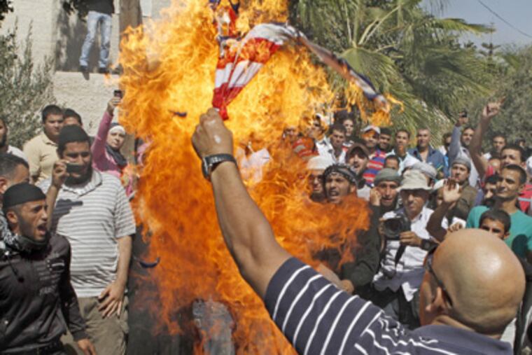 An Islamist Jordanian protester burns the U.S. flag near the U.S. embassy in Amman, Jordan, Friday, Sept. 14, 2012, as part of anger across the Muslim world about a film ridiculing Islam's Prophet Muhammad. (AP Photo/Raad Adayleh)