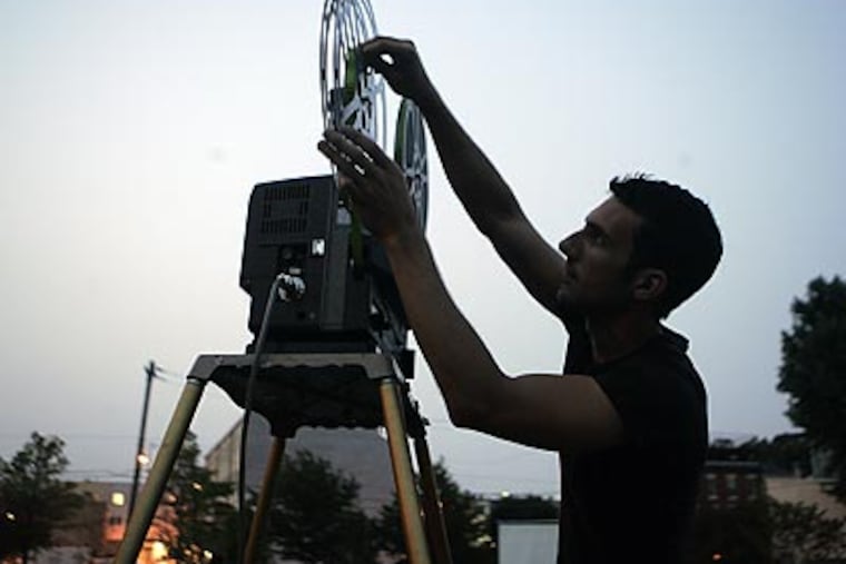 Dave Amodei prepares the projector at a Liberty Lands movie screening. (Bonnie Weller/Staff Photographer)