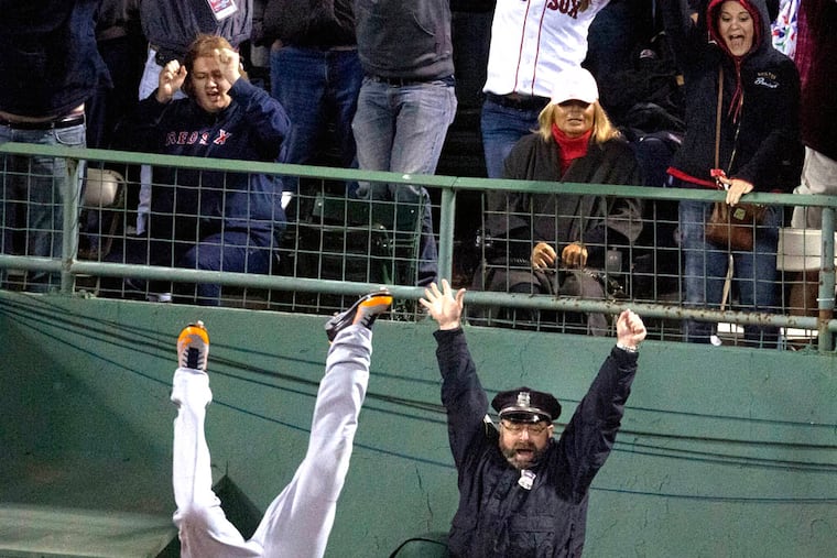 Boston police officer Steve Horgan raises his arms in celebration as Tigers' Torii Hunter goes head over heels while failing to catch grandslam hit by Red Sox' David Ortiz during Game 2 of the ALCS. (Associated Press)