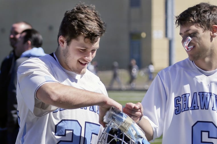 Shawnee HS lacrosse goalkeeper Dan Falzone (left) gets a fist-pump from teammate Tom Shinske.