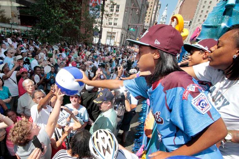(L-R) Eli Simon, Mo'ne Davis and Zion Spearman signed a beach ball and then handed it to a particular fan at the Kimmel Center during the parade for the Taney Dragons in Phila. on Aug. 27, 2014. ( ELIZABETH ROBERTSON / Staff Photographer )