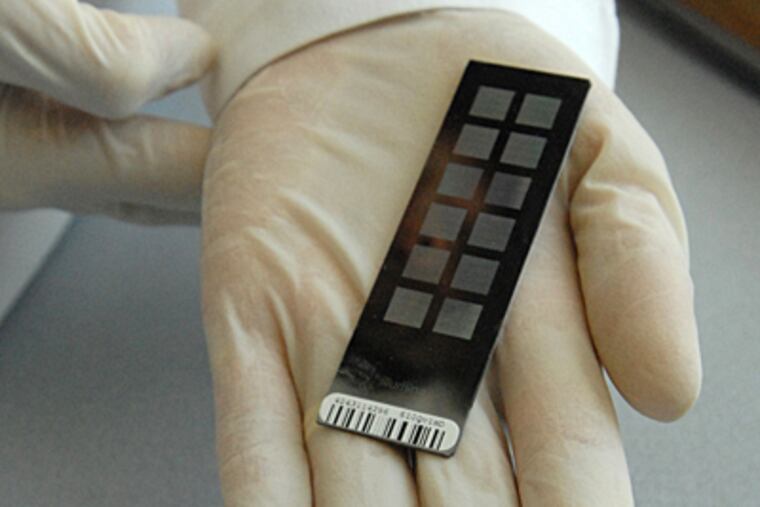 At CHOP, lab manager Cecilia Kim holds a bead chip which contains genetic variance for the neuroblastoma analysis. (April Saul / Inquirer)