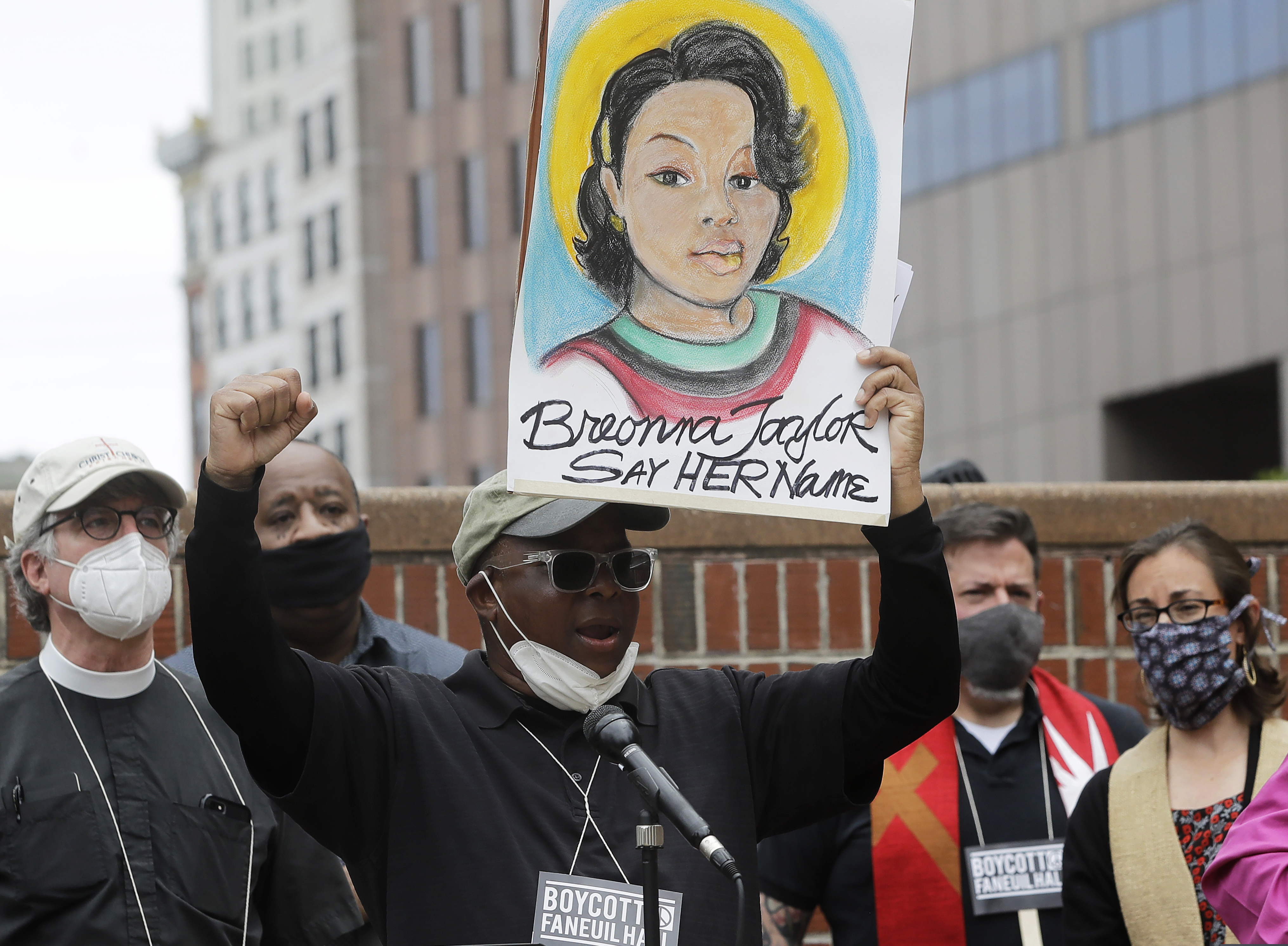 In this June 9 photo, Kevin Peterson, center, founder and executive director of the New Democracy Coalition, displays a placard showing Breonna Taylor as he addresses a rally in Boston.