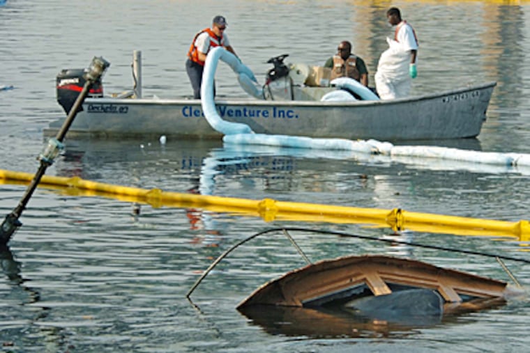 Workers try to soak up leaking fuel from two tugboats that sunk near Girard Point on the Schuylkill. (Clem Murray / Inquirer)