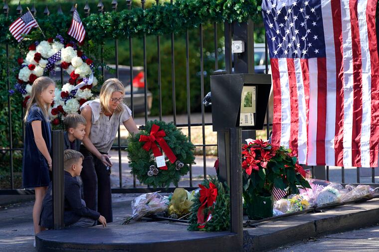 Tiffany Utterson, right, and her children, from left to right, Ella, 11, Ian, 10 and Owen, 8, place a wreath outside the gated community entrance to the home of George H.W. Bush Sunday, Dec. 2, 2018, in Houston. Bush is returning to Washington as a revered political statesman, hailed by leaders across the political spectrum and around the world as a man not only of greatness but also of uncommon decency and kindness. Bush, died late Friday at his Houston home at age 94, is to be honored with a state funeral at National Cathedral in the nation's capital on Wednesday, followed by burial Thursday on the grounds of his presidential library at Texas A&M.(AP Photo/David J. Phillip)