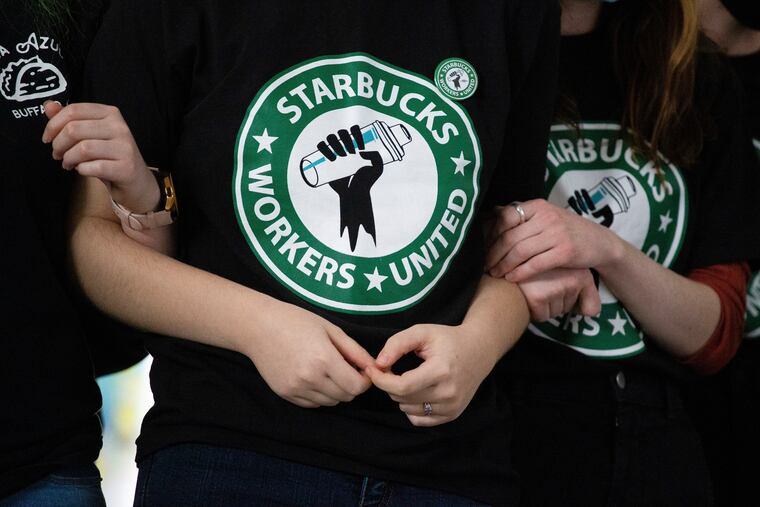 Starbucks employees and supporters link arms during a union election watch party in 2021 in Buffalo, N.Y.