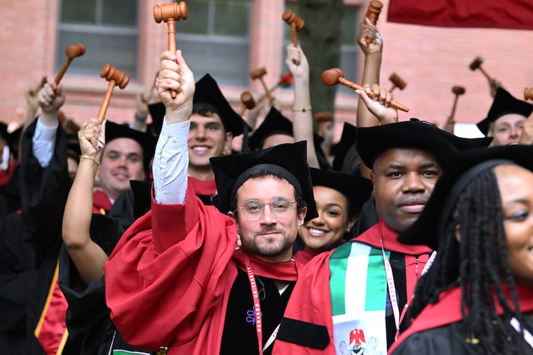 Graduates of Harvard Law School wave novelty gavels as they are conferred their degrees on May 29, 2025, in Cambridge, Mass.