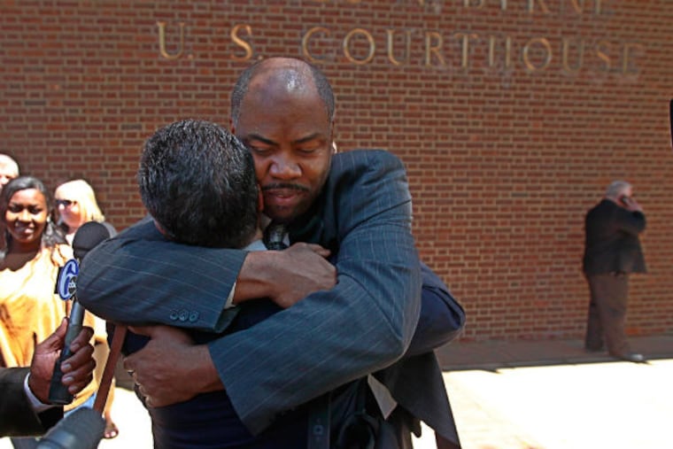 Linwood Norman, center, one of the six Philadelphia Police narcotics officers found not guilty on Thursday, gets a big hug from a family member, after coming down to Market Street after the verdict. (Michael Bryant / Staff Photographer)