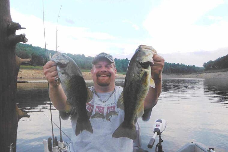 Joe Zajko, of Roxborough, with a smallmouth and largemouth bass in an undated photo. Zajko regularly catches some of the heaviest fish in the state each year.