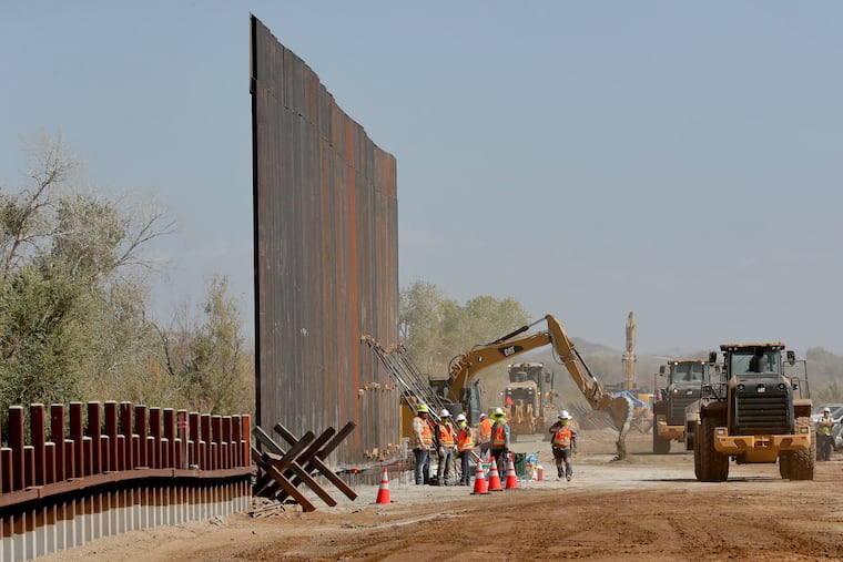 Government contractors erect a section of Pentagon-funded border wall along the Colorado River, Tuesday, Sept. 10, 2019 in Yuma, Ariz. The 30-foot high wall replaces a five-mile section of Normandy barrier and post-n-beam fencing, shown at left, along the the International border that separates Mexico and the United States. Construction began as federal officials revealed a list of Defense Department projects to be cut to pay for President Donald Trump's wall. (AP Photo/Matt York)