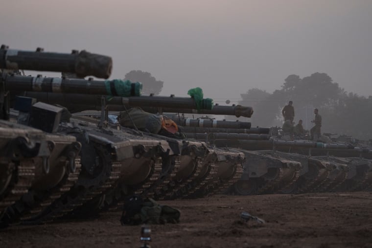 Israeli soldiers stand on top of a tank in a staging area at the Israeli-Gaza border in southern Israel on Monday, Jan. 1, 2024.