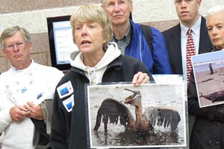 Diver Scottie Franklin holds a photo of an oil-soaked bird for a hearing on seismic testing to look for oil and natural gas deposits underneath the Atlantic Ocean. WAYNE PARRY / Associated Press