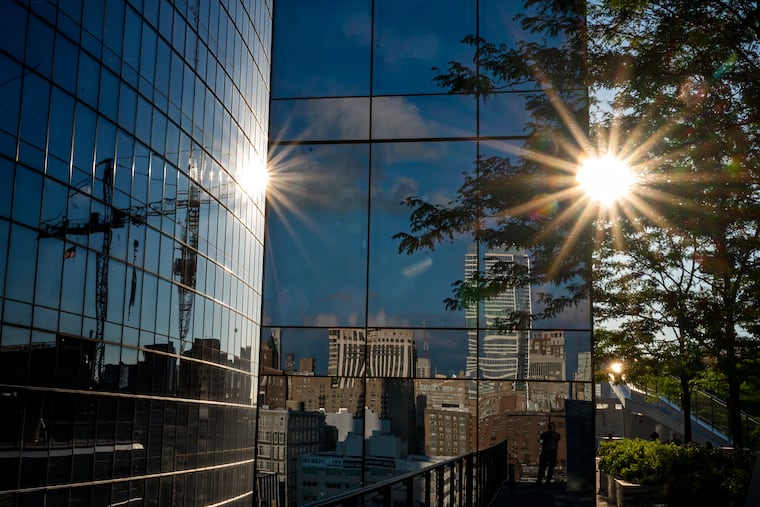 August 8, 2022: The setting sun reflects off the glass of Cira Centre South, behind the trees of the rooftop urban park Cira Green.