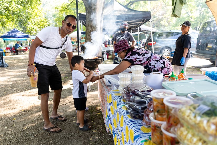 Jimmy Phy, of South Philadelphia, with his grandson Eli Phy, 2, visiting vendors to eat some food and enjoy the day at the Southeast Asian Market at FDR Park in Philadelphia on Sept. 17.