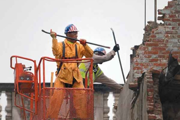 Two demolition workers with a sledgehammer and crow bars work at the remaining 4 story structure left after the collapse at 22nd and Market Streets, Friday June 7. ( DAVID SWANSON / Staff Photographer )