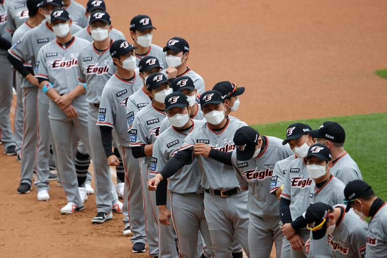 Hanwha Eagles players wearing face masks line up during the start of their regular season baseball game Tuesday against SK Wyverns in Incheon, South Korea.
