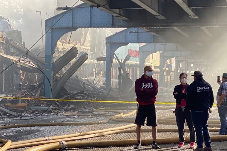 Casey O’Donnell, president and CEO of Impact Services, and Bill McKinney, executive director of New Kensington Community Development Corp., stand on the 3000 block of Kensington Avenue in front of "another symbol of the extraction of resources from residents of Kensington" — a smoldering Rent-A-Center — in June 2020.