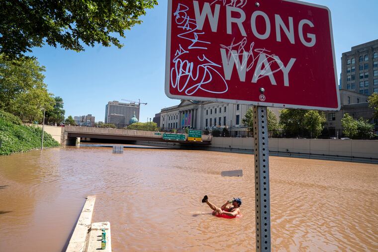 Austin Ferdock drinks a beer while floating in floodwater over the submerged Vine Street Expressway on Sept. 2.