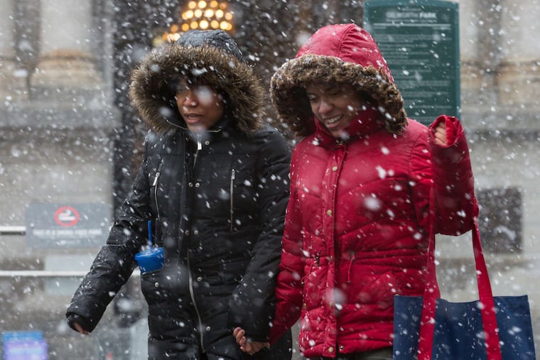 Twin sisters Amber Davis (left) and Alysia Davis make their way through Friday's storm in front of City Hall in Philadelphia.