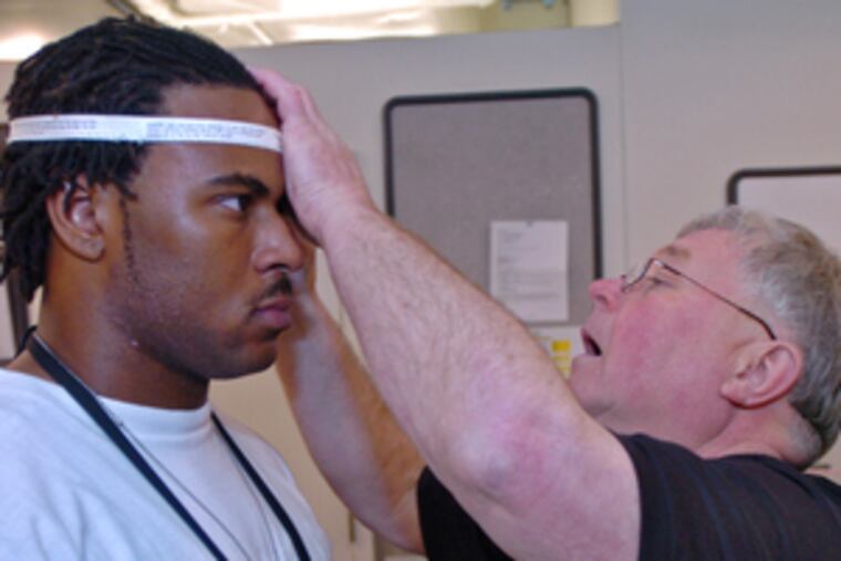 In preparation for minicamp, Eagles equipment manager John Hatfield measures undrafted rookie Marques Murrell, a defensive end from Appalachian State, for a helmet. The Eagles will have morning and afternoon practices today and tomorrow.