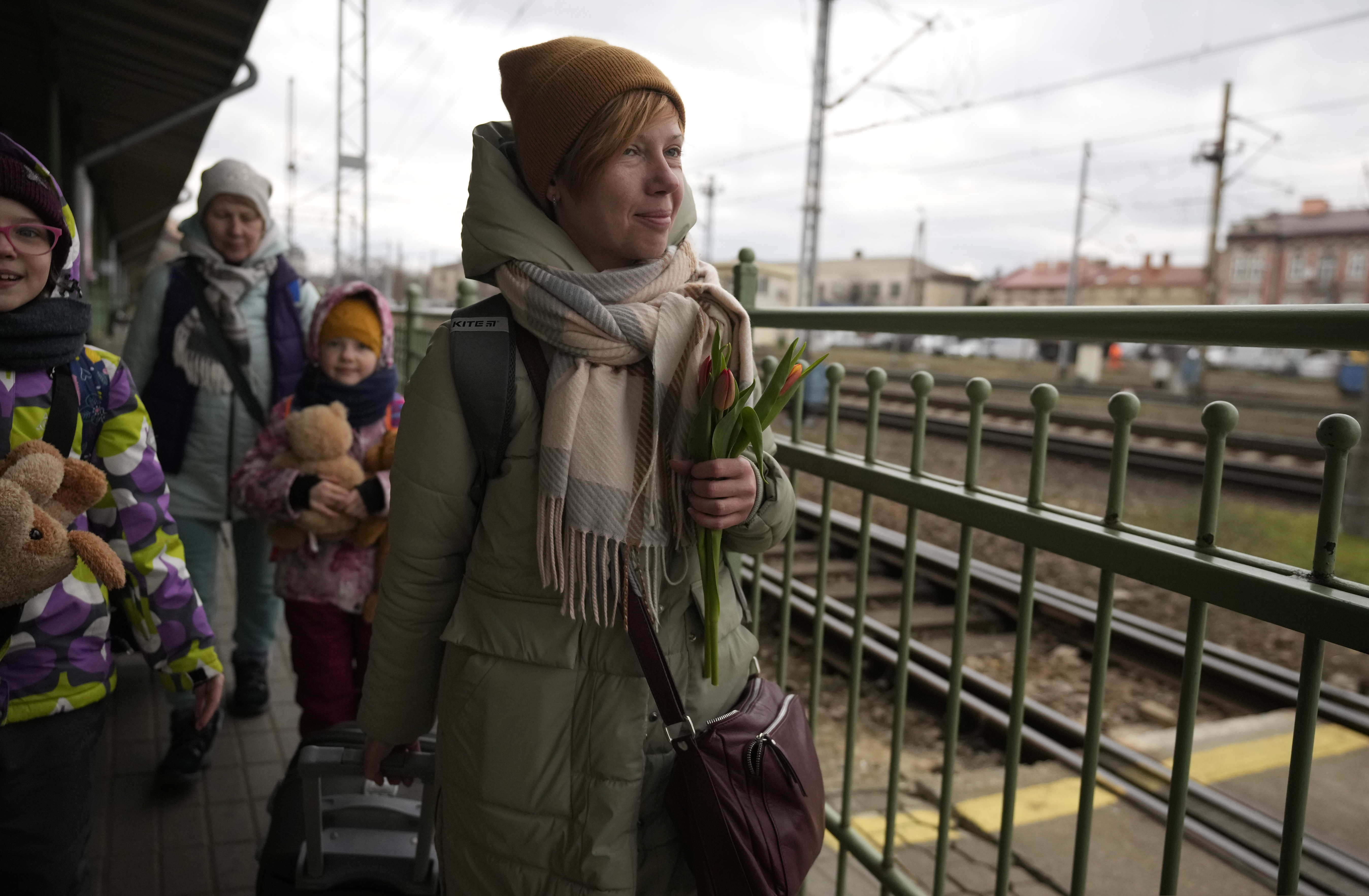 A woman, who fled Ukraine, carries tulips she received from a Catholic priest in recognition of International Women's Day, as she walks at the train station in Przemysl, Poland, Tuesday, March 8, 2022. U.N. officials said Tuesday that the Russian onslaught has forced 2 million people to flee Ukraine. It has trapped others inside besieged cities that are running low on food, water and medicine amid the biggest ground war in Europe since World War II.