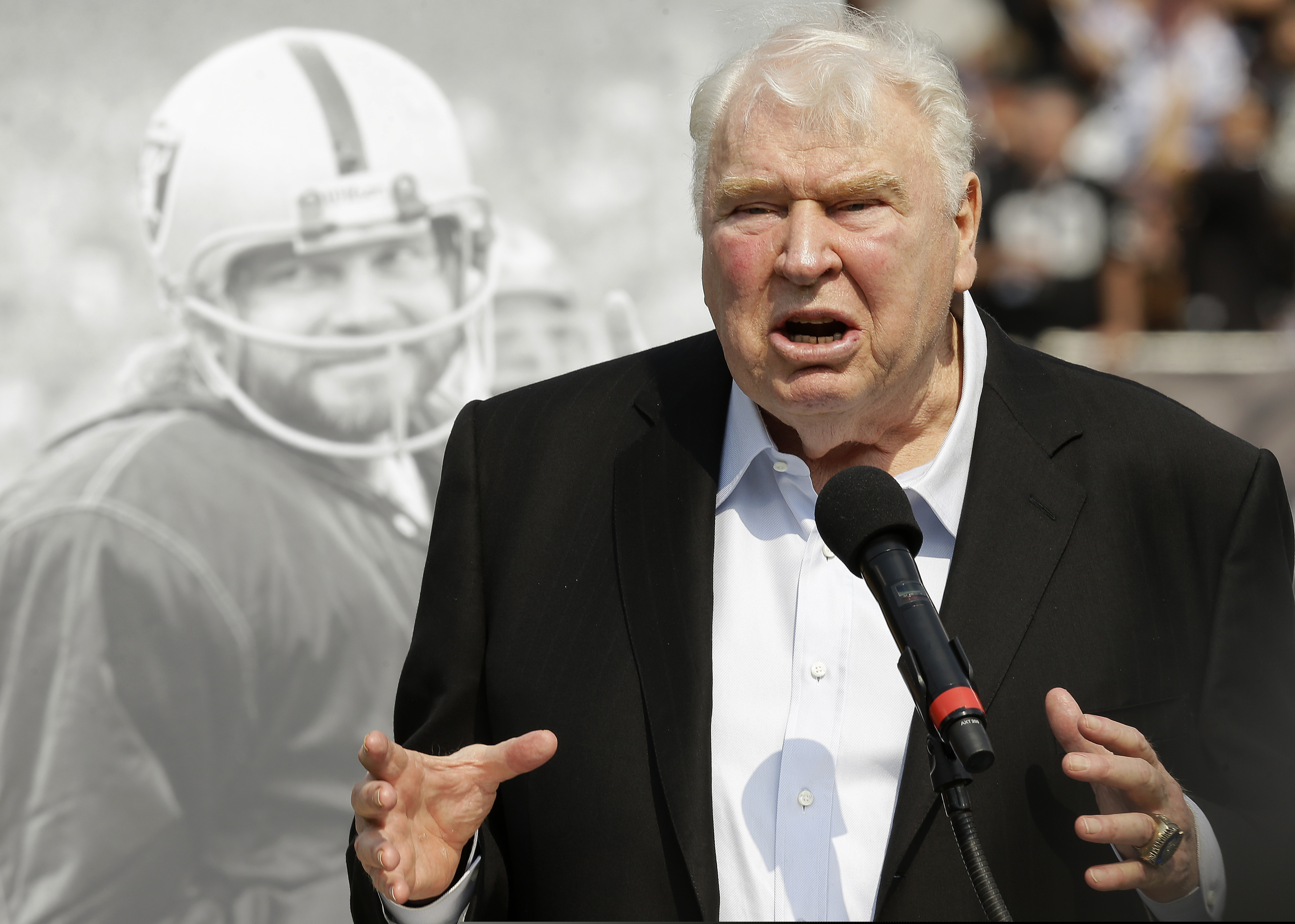 Former Oakland Raiders head coach John Madden speaks about former quarterback Ken Stabler, pictured at rear, at a ceremony honoring Stabler during halftime of an NFL football game between the Raiders and the Cincinnati Bengals in Oakland, Calif., on Sept. 13, 2015.