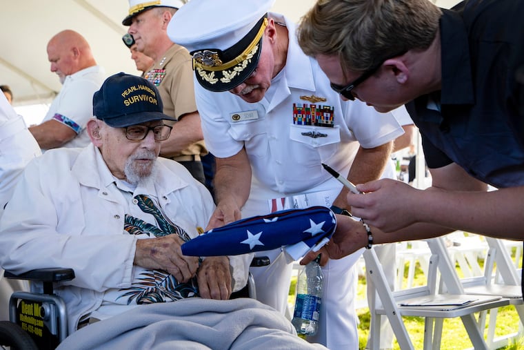 An attendee asks Pearl Harbor survivor Ira "Ike" Schab, 103, to sign an U.S. flag during the 82nd Pearl Harbor Remembrance Day ceremony on Thursday, Dec. 7, 2023, at Pearl Harbor in Honolulu, Hawaii.